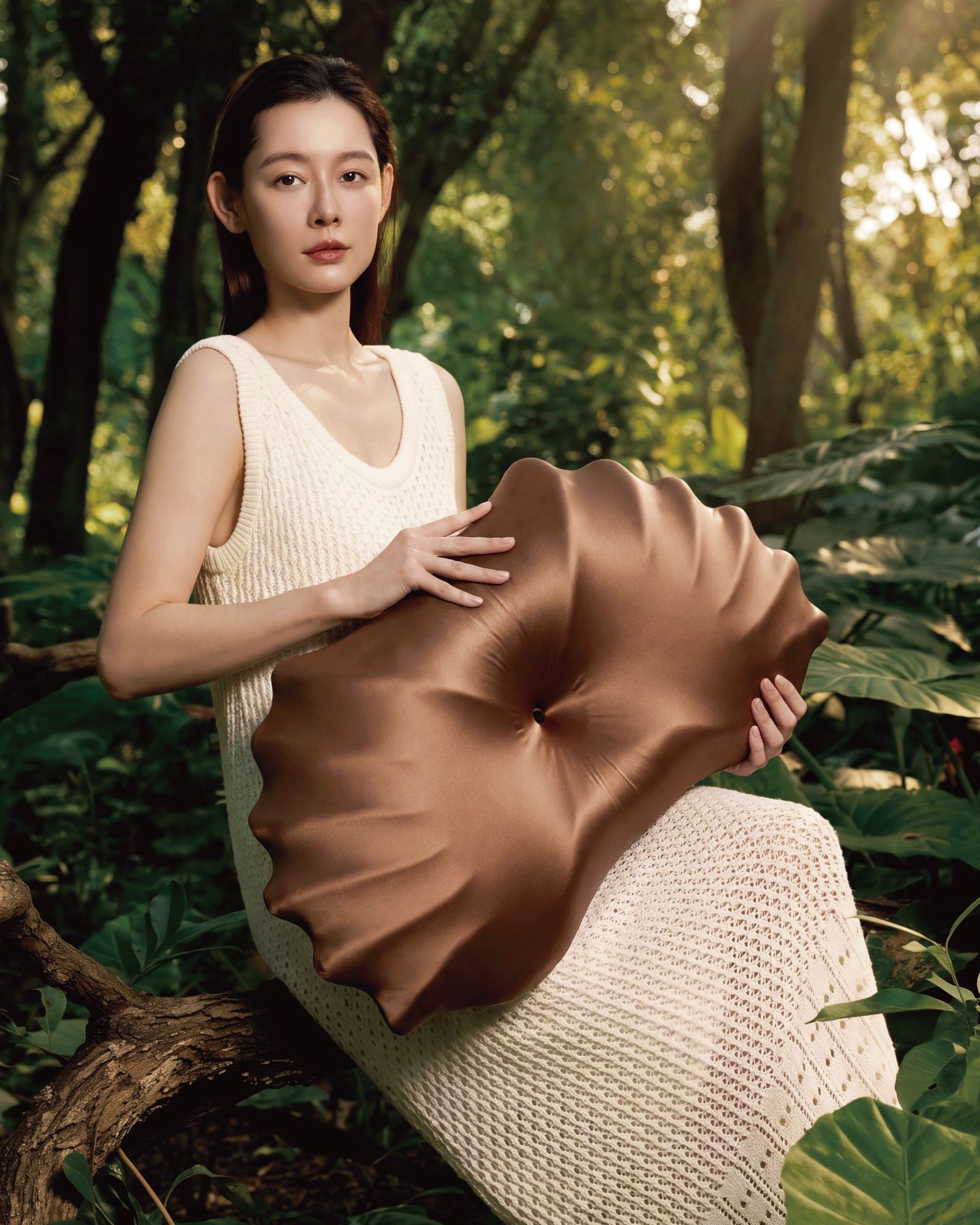 Shell-inspired brown pillow shown in a forest setting
