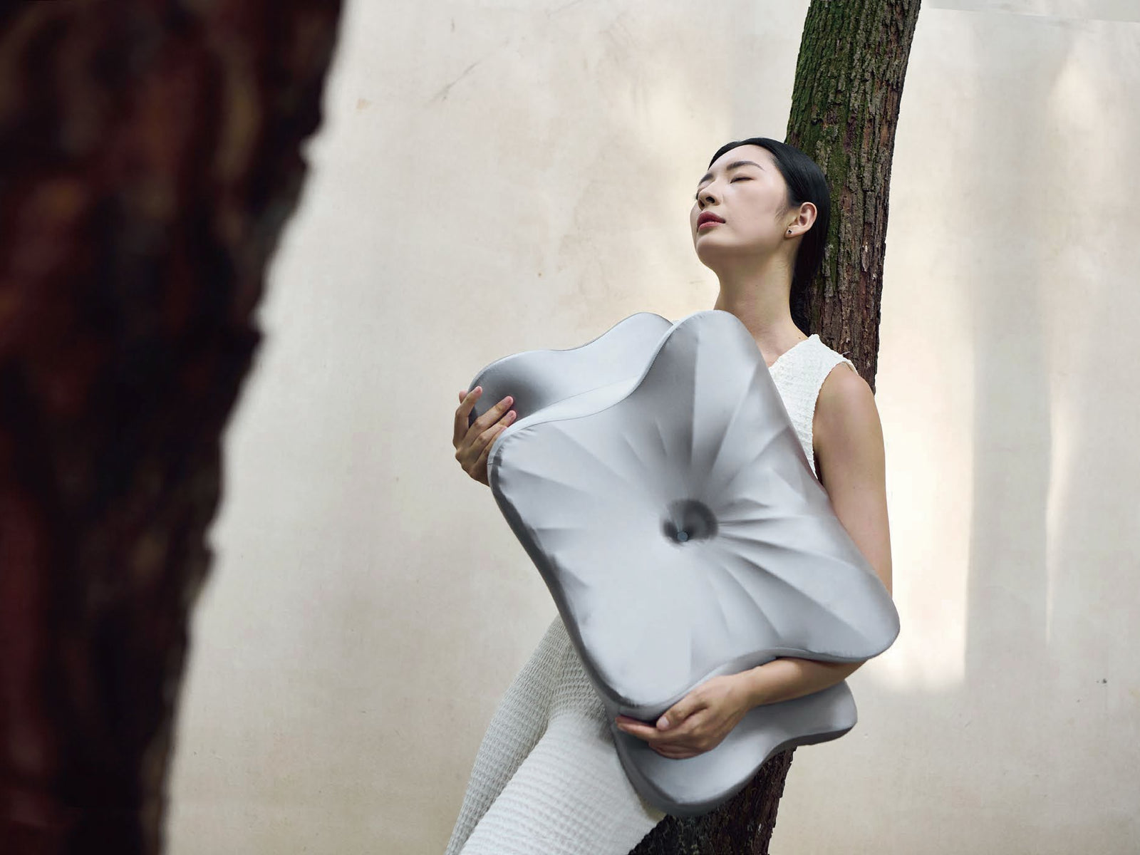 Grey contoured pillow held in a product presentation